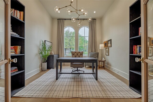 home office featuring an inviting chandelier, baseboards, and wood finished floors