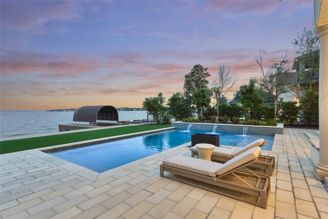 outdoor pool with a patio and a water view