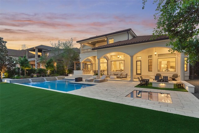 rear view of property with an outdoor living space with a fire pit, a balcony, an outdoor pool, a patio area, and a yard