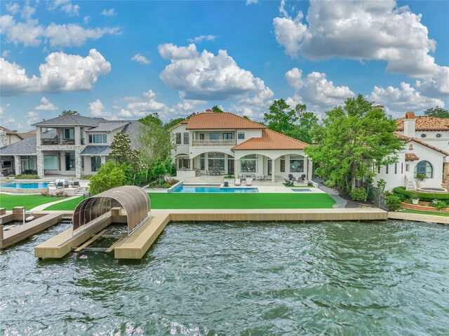 back of house featuring a balcony, a patio, a water view, and an outdoor pool