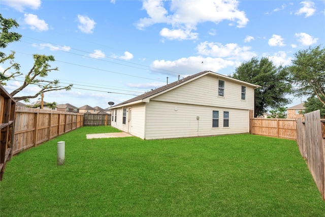 rear view of house featuring a lawn and a fenced backyard