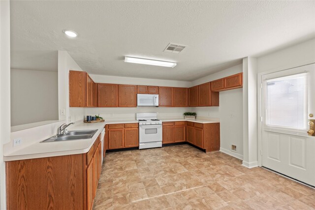 kitchen with a sink, brown cabinetry, white appliances, and visible vents