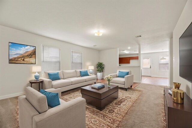 living area featuring baseboards, light colored carpet, and visible vents
