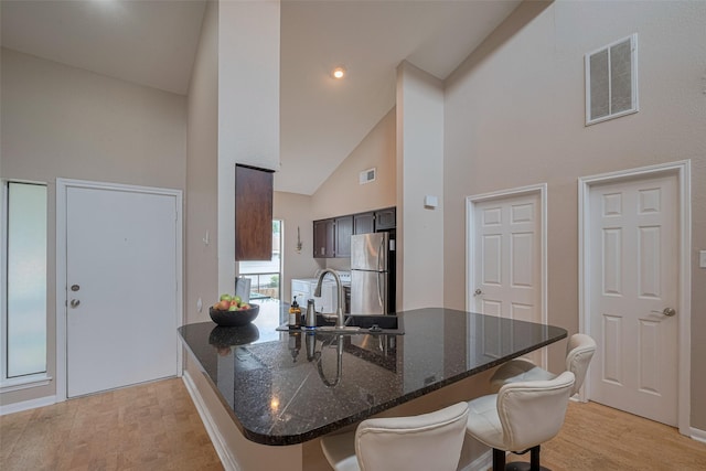 182 April Point Dr N, Conroe, TX 77356 - kitchen featuring a sink, a kitchen breakfast bar, high vaulted ceiling, freestanding refrigerator, and visible vents