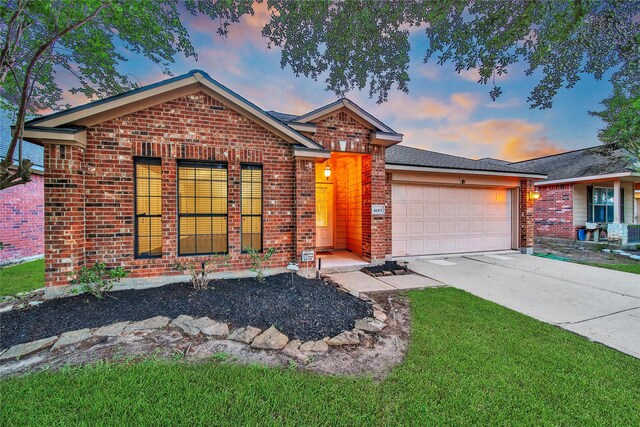single story home with concrete driveway, brick siding, an attached garage, and a yard