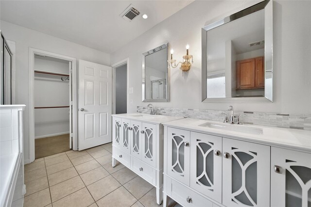 bathroom featuring visible vents, tile patterned flooring, double vanity, a walk in closet, and a sink