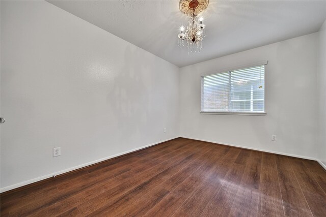 spare room featuring baseboards, a chandelier, and wood finished floors