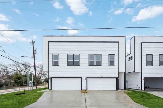 view of front of property with a garage, concrete driveway, and a front lawn