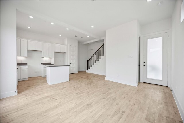 unfurnished living room with recessed lighting, baseboards, stairs, and light wood-style floors
