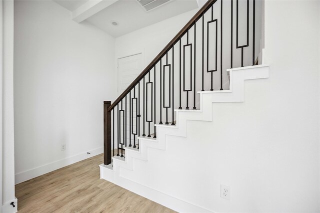 stairway with baseboards, wood finished floors, and visible vents