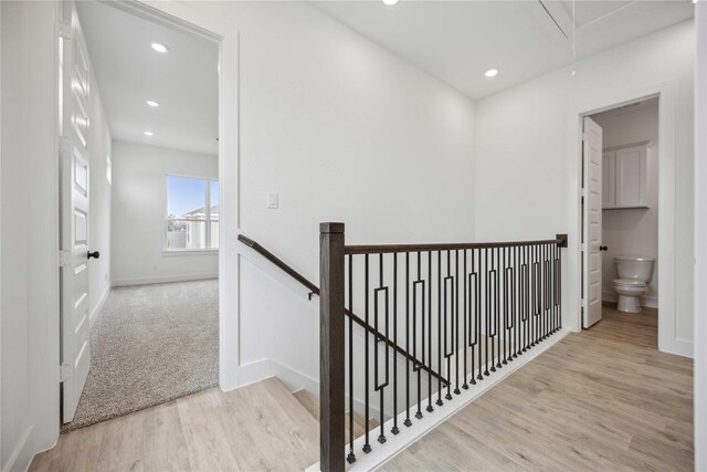 hallway featuring wood finished floors, baseboards, attic access, recessed lighting, and an upstairs landing