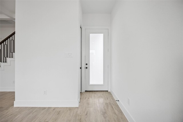 entryway with stairs, baseboards, and light wood finished floors