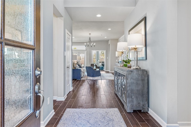entryway featuring baseboards, an inviting chandelier, and dark wood-style floors