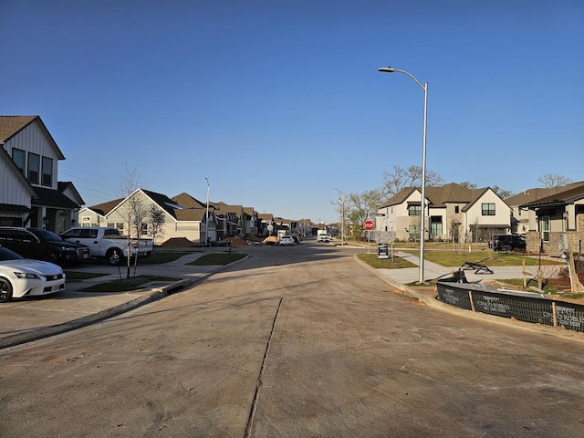 view of road with curbs, a residential view, sidewalks, street lights, and traffic signs