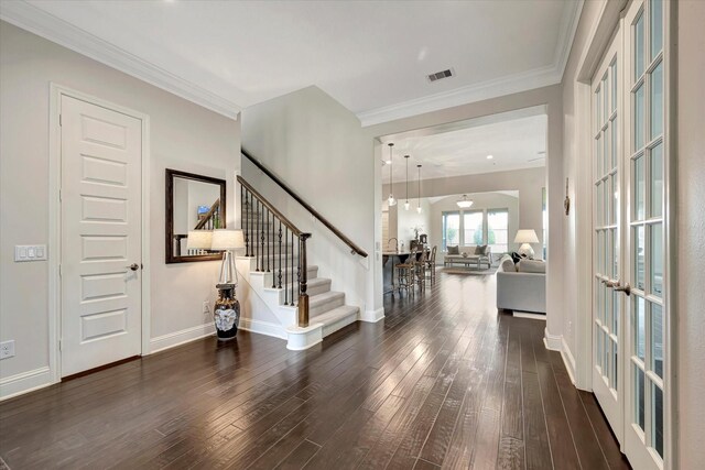 foyer entrance with crown molding, visible vents, stairs, wood finished floors, and baseboards