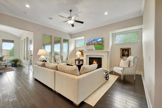 living area with a healthy amount of sunlight, ceiling fan, a glass covered fireplace, and visible vents