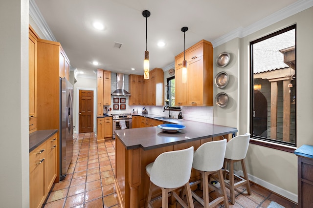 kitchen with visible vents, crown molding, appliances with stainless steel finishes, a peninsula, and wall chimney exhaust hood