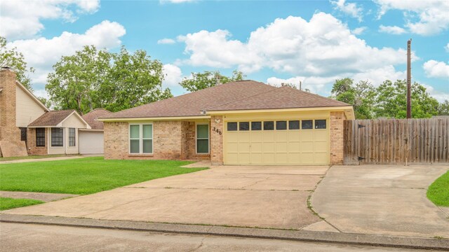 ranch-style house featuring fence, a front yard, brick siding, concrete driveway, and an attached garage