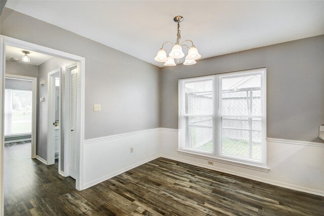 unfurnished dining area featuring an inviting chandelier, baseboards, and dark wood-type flooring