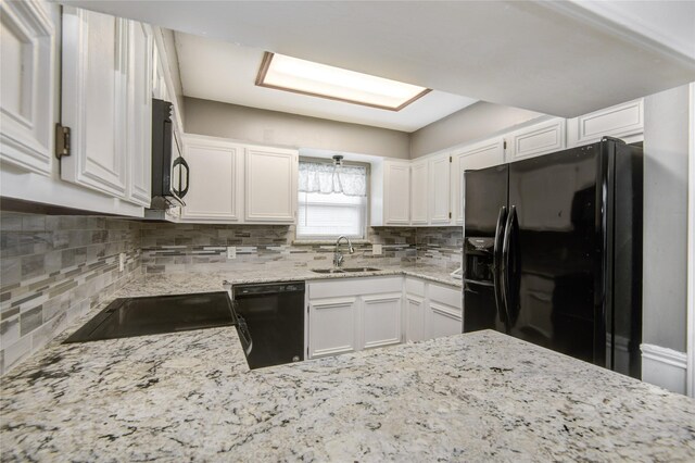 kitchen with a sink, white cabinetry, black appliances, and tasteful backsplash