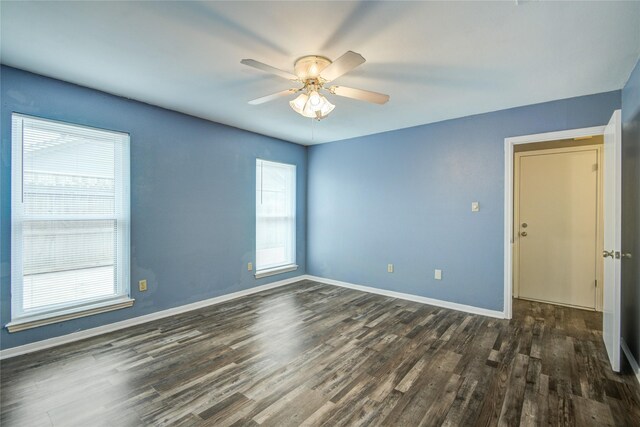 spare room with baseboards, dark wood finished floors, and ceiling fan