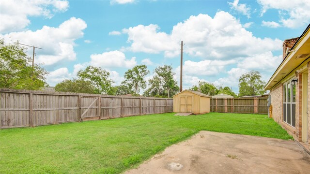 view of yard featuring a fenced backyard, a storage unit, an outbuilding, and a patio area