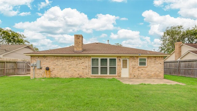 back of property featuring a fenced backyard, a chimney, a lawn, and brick siding