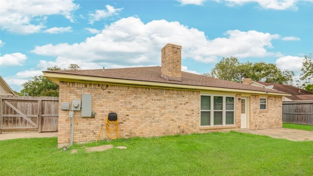 back of property with brick siding, a lawn, fence, and a chimney
