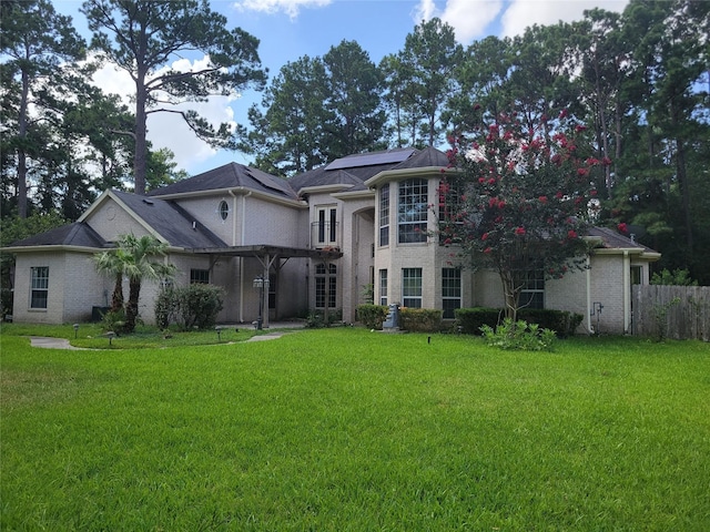 view of front of property with roof mounted solar panels, fence, a pergola, and a front yard