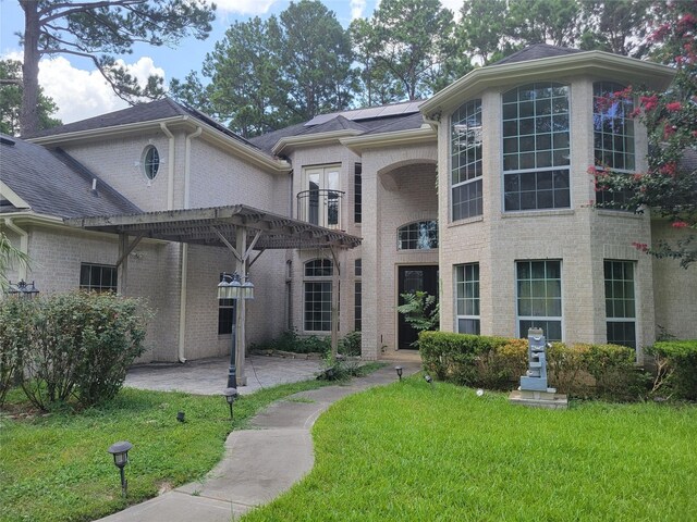view of front of property with a pergola, a patio area, brick siding, and a front yard
