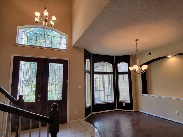 entrance foyer with tile patterned flooring, baseboards, a notable chandelier, and visible vents
