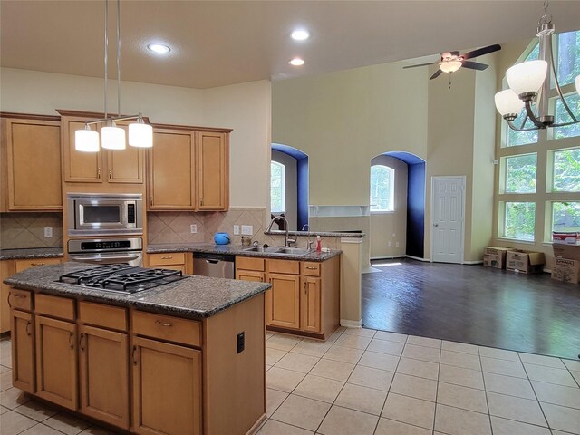 kitchen with a sink, arched walkways, stainless steel appliances, and light tile patterned flooring