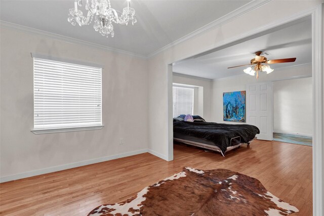 bedroom featuring baseboards, ornamental molding, wood finished floors, and ceiling fan with notable chandelier