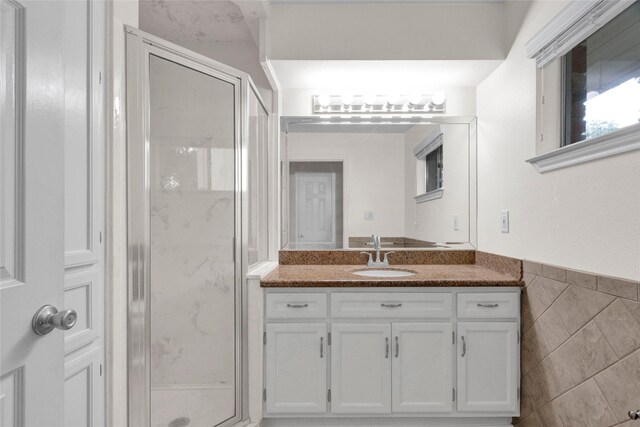 bathroom with vanity, a stall shower, and tile walls