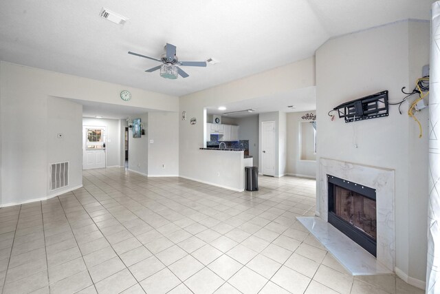 unfurnished living room featuring light tile patterned flooring, ceiling fan, visible vents, and a fireplace