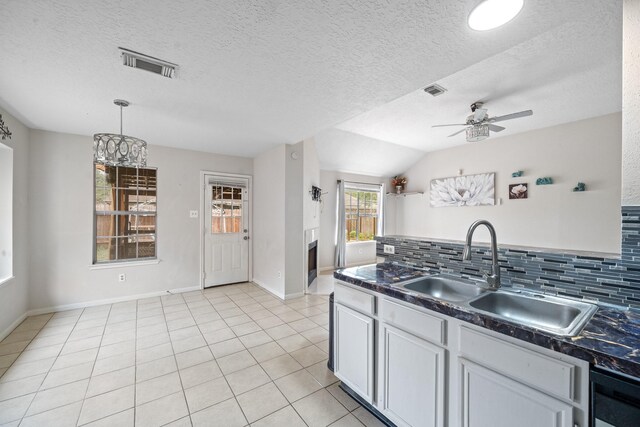 kitchen featuring visible vents, a ceiling fan, dark countertops, a sink, and backsplash