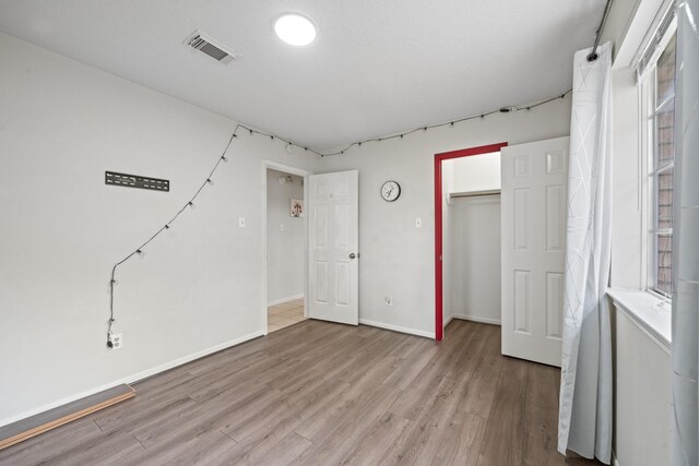 unfurnished bedroom with a closet, baseboards, visible vents, and light wood-style floors