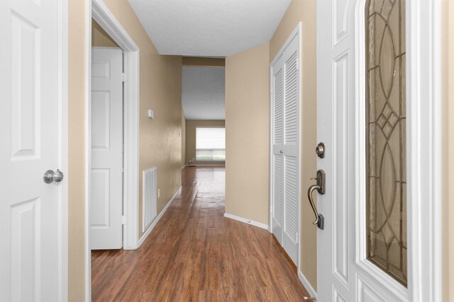 corridor with baseboards, dark wood-style floors, and visible vents