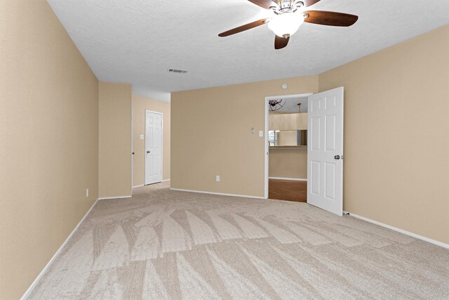 carpeted spare room with baseboards, a ceiling fan, a textured ceiling, and visible vents