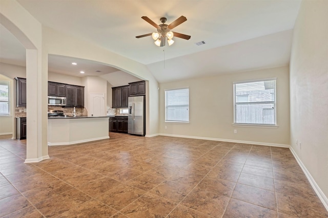 unfurnished living room with visible vents, arched walkways, ceiling fan, and light tile patterned flooring