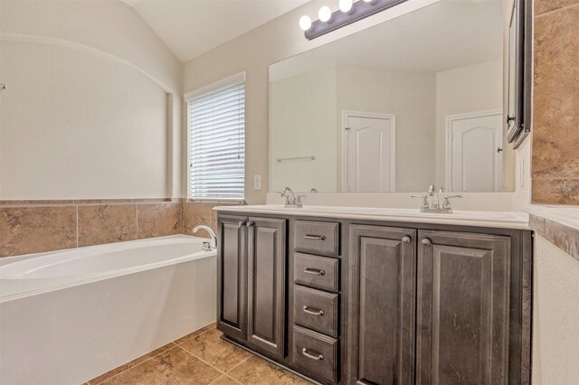 bathroom with double vanity, a sink, lofted ceiling, and a bath