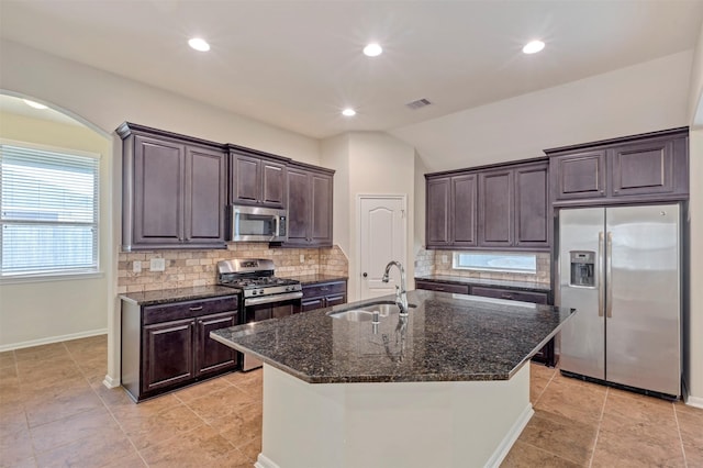 kitchen featuring dark brown cabinetry, appliances with stainless steel finishes, a sink, arched walkways, and visible vents