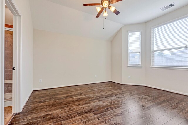 spare room featuring visible vents, lofted ceiling, baseboards, ceiling fan, and dark wood-type flooring