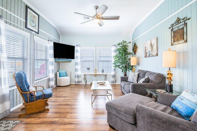 living area featuring baseboards, ceiling fan, wood finished floors, and visible vents