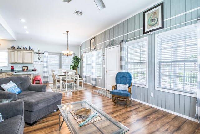 living area with baseboards, a notable chandelier, wood finished floors, and visible vents