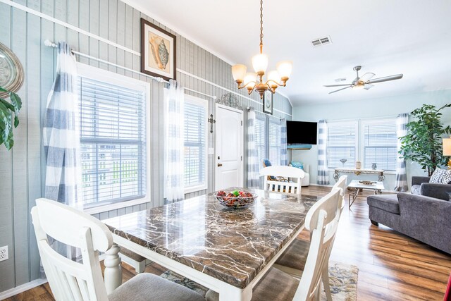 dining space with ceiling fan with notable chandelier, wood finished floors, and visible vents