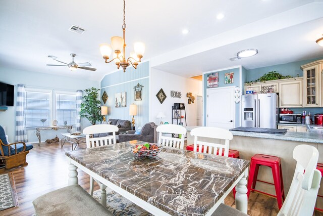dining space featuring ceiling fan with notable chandelier, recessed lighting, wood finished floors, lofted ceiling, and visible vents