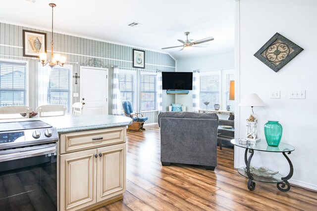 kitchen with stainless steel electric range oven, cream cabinets, light wood-style floors, ceiling fan with notable chandelier, and visible vents