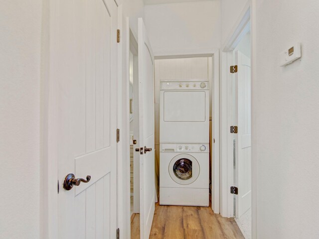 washroom featuring laundry area, stacked washer / dryer, and light wood-style flooring