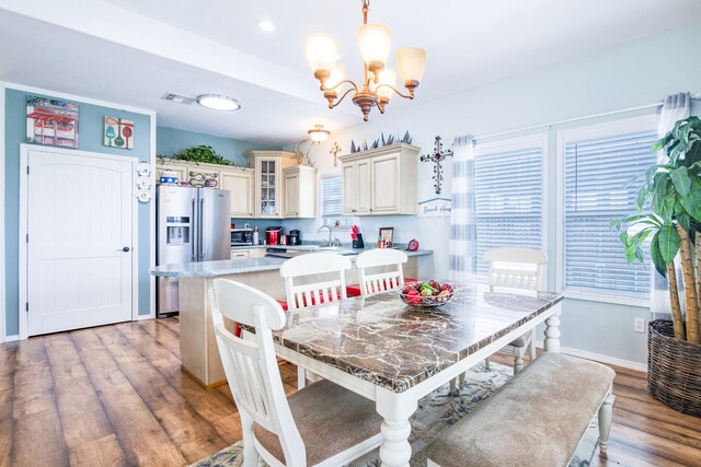 dining area featuring baseboards, light wood-type flooring, and a notable chandelier